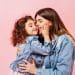 Relaxed Preteen Girl Embracing With Mother. Winsome Young Mom Kissing Daughter On Pink Background